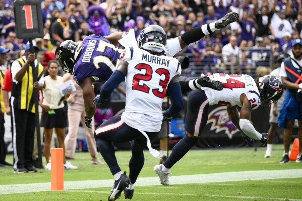 JK Dobbins của Baltimore Ravens vượt qua Derek Stingley Jr. (24) và Eric Murray (23) của Houston Texans để có một pha chạm bóng trong hiệp một của trận đấu bóng đá NFL vào Chủ Nhật, ngày 10 tháng 9 năm 2023, tại Baltimore. (Ảnh AP/Nick Wass)