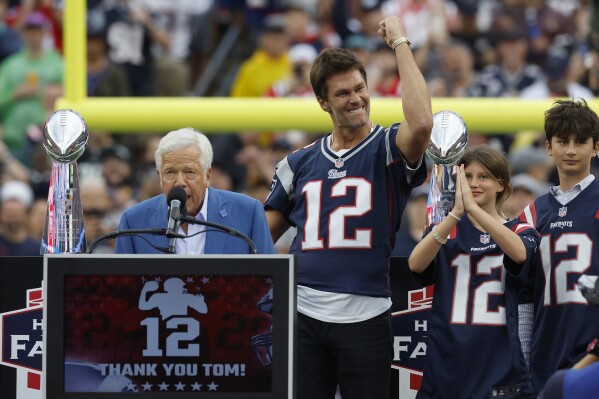 Former New England Patriots quarterback Tom Brady, second from left, gestures as Patriots owner Robert Kraft, left, addresses the crowd while Brady's daughter Vivian, second from right, and son Benjamin, right, look on during halftime ceremonies held to honor Brady at an NFL football game between the Philadelphia Eagles and the Patriots, Sunday, Sept. 10, 2023, in Foxborough, Mass. (AP Photo/Mark Stockwell)